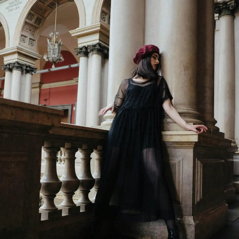 Elegant woman in a red beret posing in a grand historic setting, showcasing luxury fashion