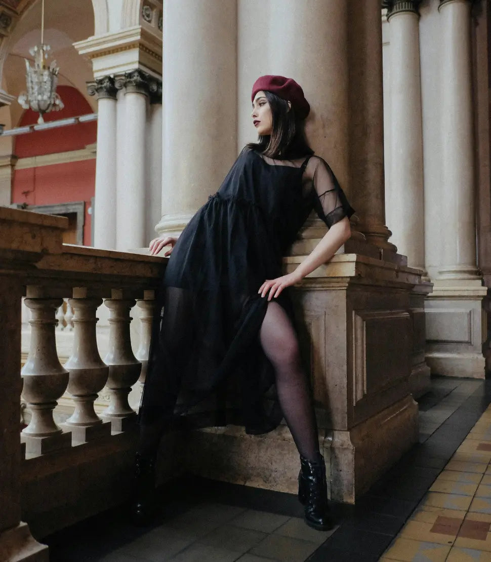 Woman in a chic black dress and red beret posing elegantly by classical architecture